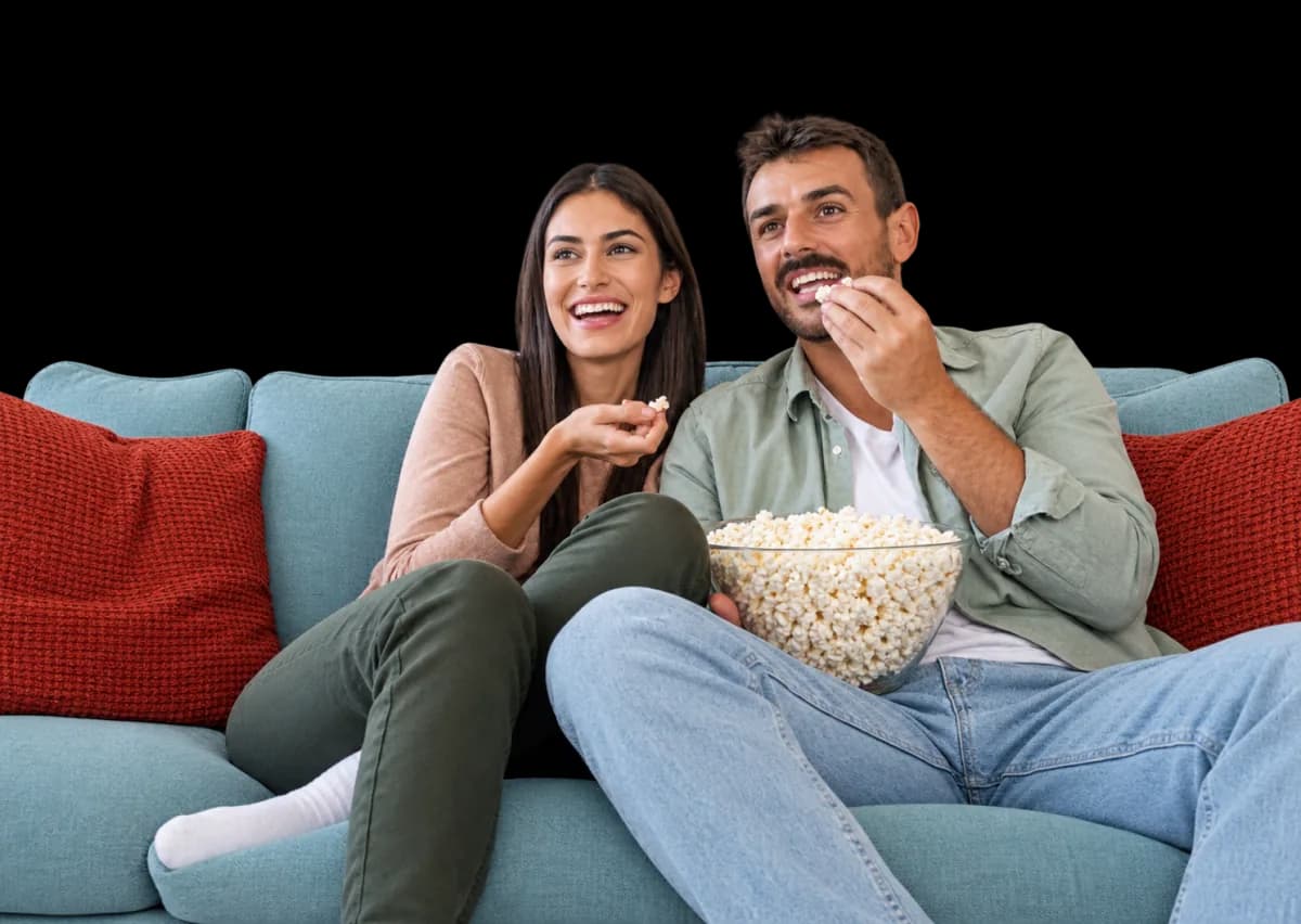 Una pareja ve una película en el sofá mientras comparte palomitas
